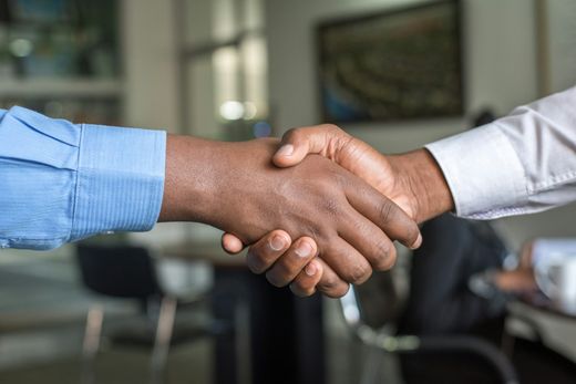 Zwei Personen geben sich in einem Büro die Hand