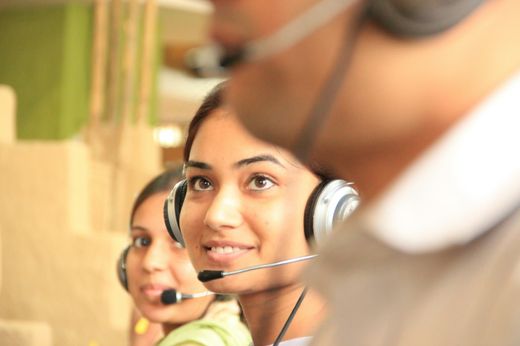 Zwei Personen mit Headsets an ihren Arbeitsplätzen
